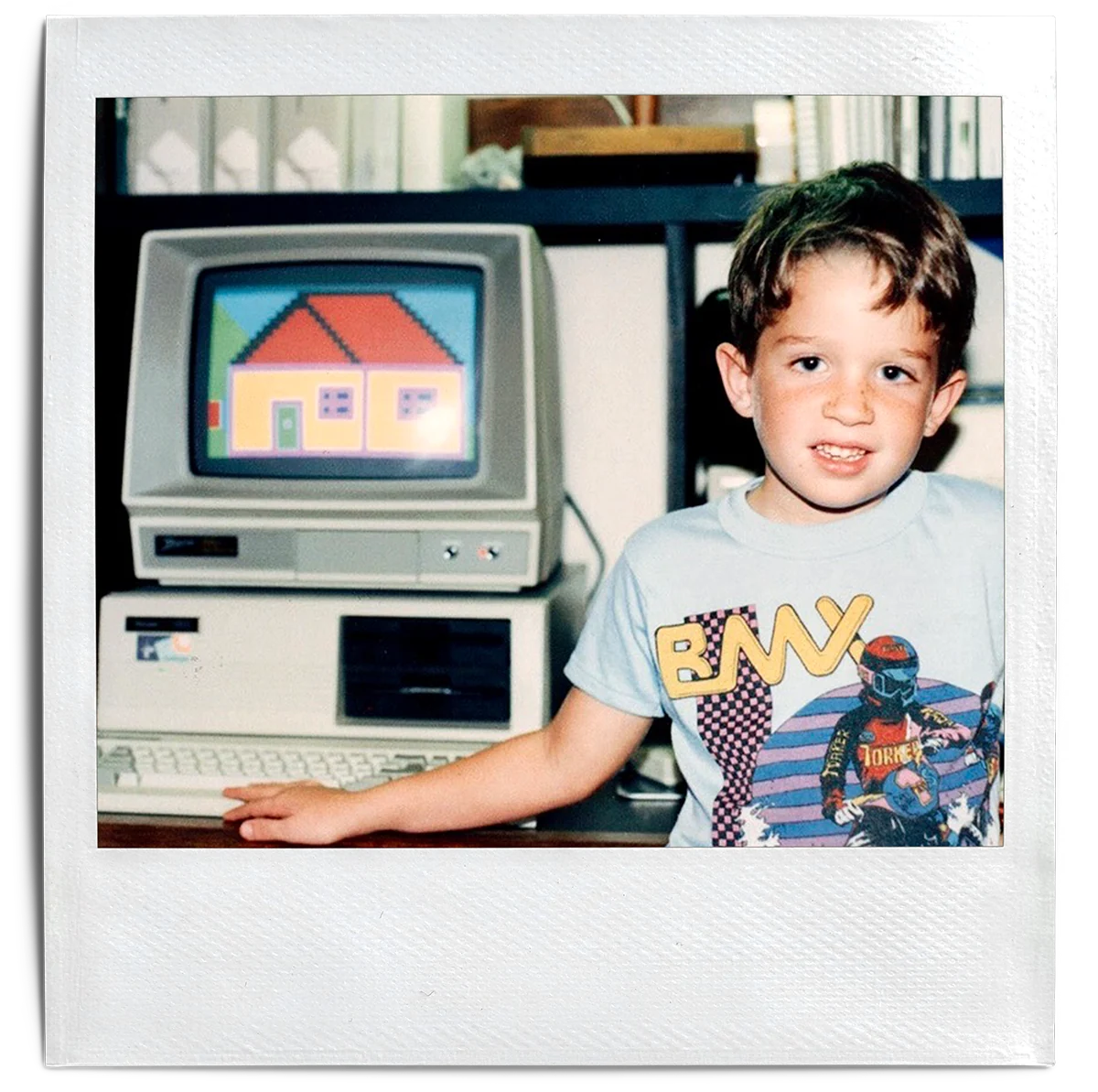 Joey Wright at about five years old beside an IBM computer displaying a colorful house he made